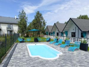 a swimming pool with chairs and an umbrella and a house at Domki Kompas in Jantar