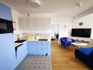 a kitchen and living room with a blue couch at Aravell E23 Darłówko Wschodnie in Darlowko