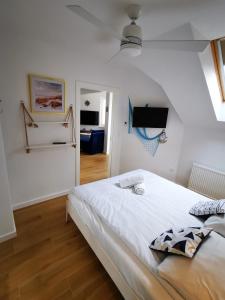 a white bedroom with a bed and a flat screen tv at Aravell E23 Darłówko Wschodnie in Darlowko
