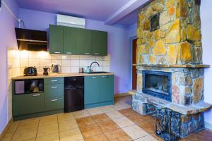 a kitchen with a stone fireplace in a room at Całoroczne Domki w Bieszczadach "The Willows" in Łączki
