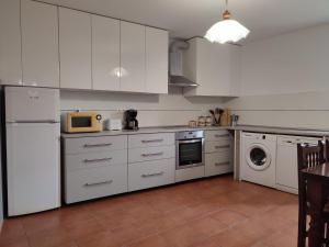 a kitchen with white cabinets and a washer and dryer at Casa Floriña in Outes