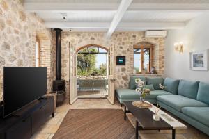 a living room with a couch and a tv at Corfu OliveStone Village with Swimming pool in Ágios Márkos