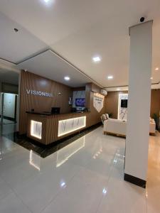 a lobby with a couch and a television in a building at Visionsul Hotel in Chapadão do Sul