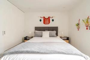 Un dormitorio con una cama blanca con dos mesitas de noche. en Premiere apartment in the heart of Barranco, a block away from Central restaurant, en Lima