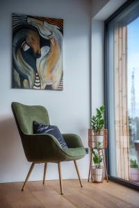 a green chair in a room with a painting at Hotel Frost in Maribor