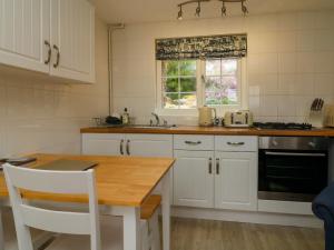 eine Küche mit weißen Schränken und einem Holztisch in der Unterkunft Martin Cottage in Berrynarbor