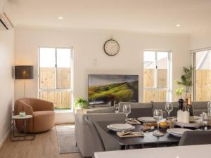 a living room with a table and chairs and a clock at Modern Family Retreat in Premier GreenbankLocation in Springfield Lakes