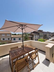 a wooden table with an umbrella on a balcony at Maison de village avec terrasse in Grans