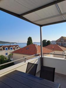 a balcony with a table and chairs and a view of the water at Smokvica - NEW in Primošten