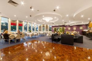 un comedor con mesas, sillas y ventanas en Ciloms Airport Lodge, en Melbourne