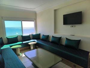 a living room with a blue couch and a flat screen tv at Appartement Spacieux et Accueillant avec Vue Panoramique sur la Mer in Martil +18 photos