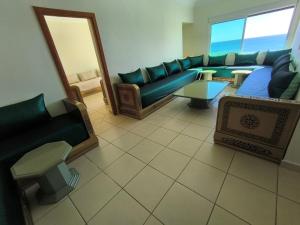 a living room with a blue couch and a mirror at Appartement Spacieux et Accueillant avec Vue Panoramique sur la Mer in Martil