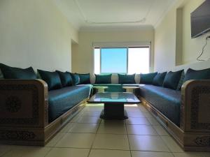 a living room with a blue couch and a table at Appartement Spacieux et Accueillant avec Vue Panoramique sur la Mer in Martil