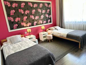 a bedroom with two beds and a painting on the wall at Lauvas Līcis in Rūjiena