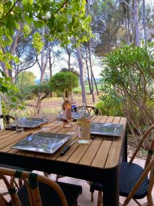 une table en bois avec des assiettes et des verres dans l'établissement Gîte Confortable Vue Exceptionnelle - Golf de Saumane, à Saumane-de-Vaucluse