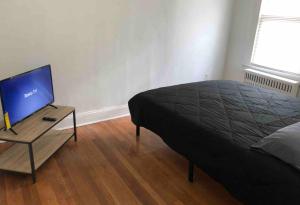 a bedroom with a bed and a table with a television at Spacious 2 bedroom apartment with 1 bathroom and private street entrance in Paterson +7 photos