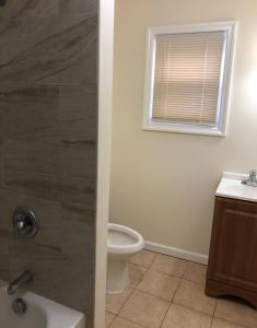 a bathroom with a shower and a toilet and a window at Large and private 3 bedroom and 1 bathroom apartment near Newark International Airport EWR and New York City in Newark