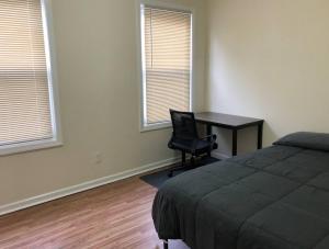 a bedroom with a desk and a bed and two windows at Large and private 3 bedroom and 1 bathroom apartment near Newark International Airport EWR and New York City in Newark