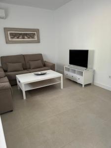 a living room with a couch and a table and a tv at Alojamiento Baeza California 2A in Baeza