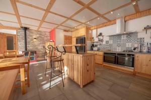 a large kitchen with wooden cabinets and a table and chairs at LE CHALET BAZAN in Arvieux
