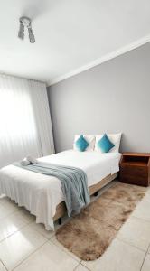 a bedroom with a large white bed with blue pillows at Quarto aconchegante no centro de Brasília in Brasilia