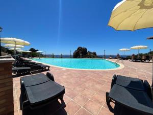 a swimming pool with chairs and umbrellas at L'Incanto Tanca Piras in Nebida