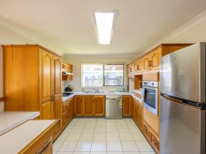 a kitchen with wooden cabinets and a stainless steel refrigerator at 4 Beds Family House at Sunnybank Hills in Brisbane +6 photos