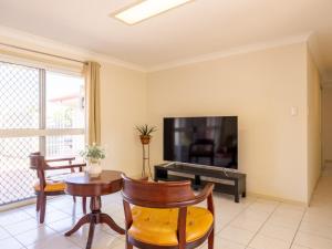 a living room with a tv and a table and chairs at 4 Beds Family House at Sunnybank Hills in Brisbane