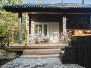 a house with a deck with two chairs on it at Hapsal Forest Cabin in Haapsalu