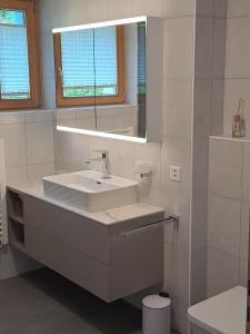 Un baño blanco con lavabo y espejo. en Chasa Azura, en Scuol