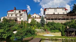 a large white house next to a lake and a house at WDZYDZANIN in Wdzydze Tucholskie