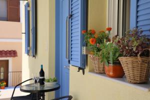 a window sill with flowers and a table with a bottle of wine at SOL Aegina Town House in Egina