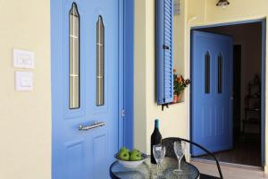 a blue door and a table with a bowl of apples at SOL Aegina Town House in Egina +25 photos