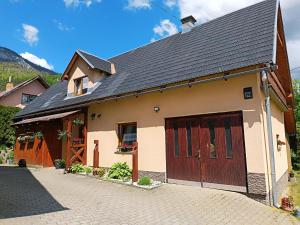 a house with a garage with two brown doors at Vilka Tkáč in Kvačany