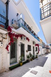 a white building with red flowers on a street at Οdyssey Apartments Lefkas Centrum in Lefkada