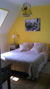 una camera da letto con un grande letto con una parete gialla di Chambre d'hôtes La Maison du Neuilly a Le Conquet
