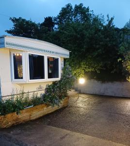 a small house with a window and some flowers at Midden Manor: Farm stay in rural County Antrim. in Cullybackey