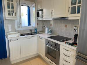 a kitchen with white cabinets and a sink at Karras House in Kimolos