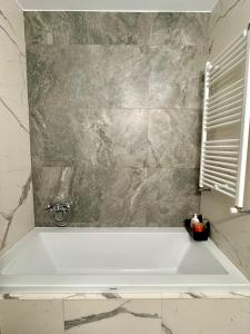 a bath tub in a bathroom with a marble wall at Cozy Apartment in Bucharest +9 photos