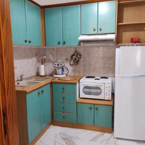 a kitchen with blue cabinets and a white refrigerator at Voukamvilia apartment in Paralia Kimis