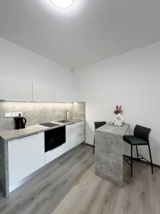 a kitchen with white cabinets and a sink and a table at DMR APARTMENTS Parkview in Košice +11 photos