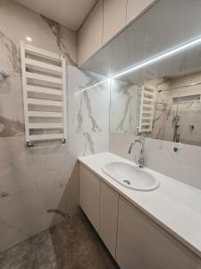 une salle de bain blanche avec un lavabo et un miroir dans l'établissement Apartament Szymanowskiego 15, à Toruń 8 autres photos