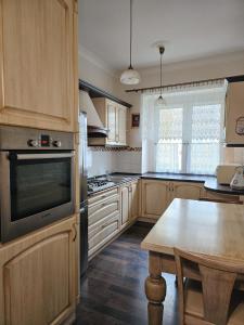 une cuisine avec des armoires en bois et une table à l'intérieur dans l'établissement Apartament Szymanowskiego 15, à Toruń