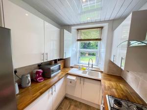a kitchen with white cabinets and a sink and a window at Lovely two bedrooms in Edinburgh +21 photos