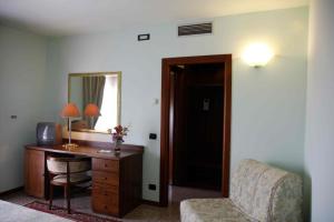 Cette chambre comprend un bureau, une chaise et un miroir. dans l'établissement Hotel Bracco, à Loreggia