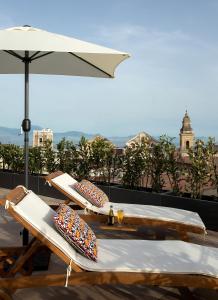 due sedie a sdraio e un ombrellone sul tetto di Galleria Port'Alba - Suites & Rooftop a Napoli