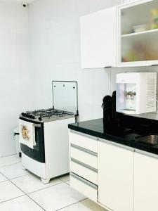a white kitchen with a stove and white cabinets at Hostel Recanto da Paciência in Salvador