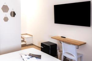 a room with a table and a tv on the wall at Art Boutique Rooms in Le Castella