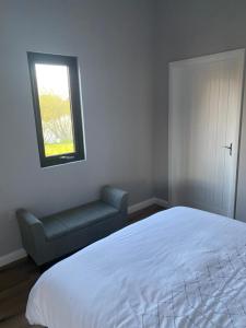 a bedroom with a bed and a window and a chair at Killyfole lakeside lodges in Corranny