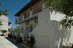 a white building with a balcony and flowers on the side at Likourgos Beach in Kavos